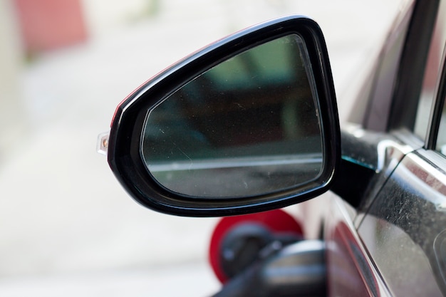 Photo close-up détail partie de sale arrière vue latérale miroir de voiture avec une réflexion floue sur fond blanc copie espace. transport, sécurité, technologie moderne et concept de conception de véhicules.