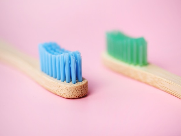 Close up de deux brosses à dents en bambou sur fond rose