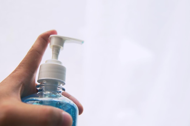 Photo close-up d'un distributeur de savon à la main sur un fond blanc