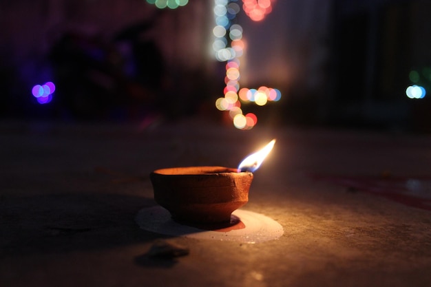 Close-up d'un diya éclairé contre des lumières défocalisées la nuit