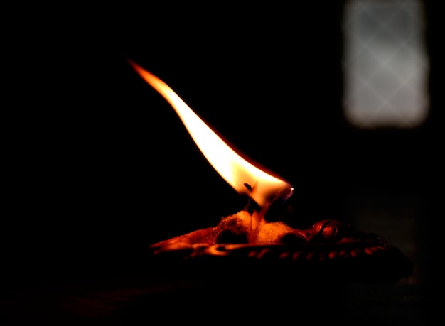 Close-up d'une diya éclairée dans une chambre noire