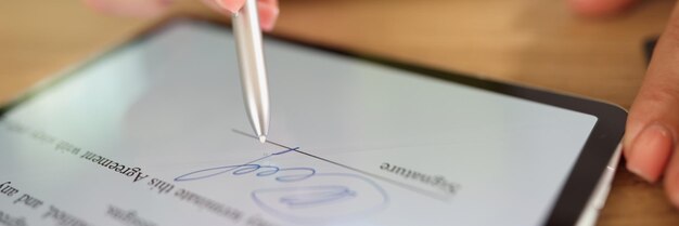 Close-up d'un document éducatif signé à la main par une femme sur une tablette avec une signature électronique au stylet et une signature moderne