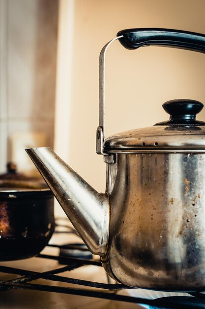 Photo close-up du chauffage de la bouilloire sur le brûleur dans la cuisine à la maison