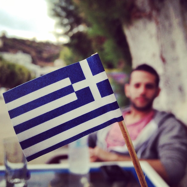 Photo close-up du drapeau grec avec un homme en arrière-plan