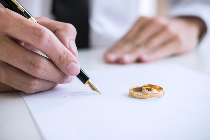 Photo close-up du juge écrivant avec des bagues de mariage sur papier