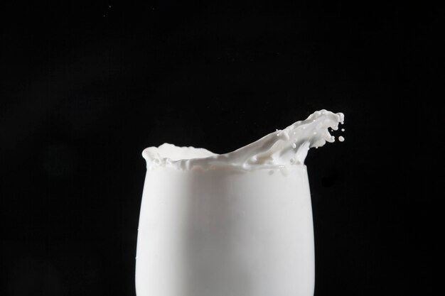 Photo close-up du lait éclaboussant dans le verre sur un fond noir