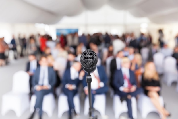 Photo close-up du microphone avec des hommes d'affaires assis en arrière-plan pendant le séminaire