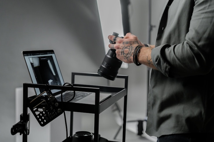 Photo close-up du photographe caucasien tenant une caméra professionnelle dans un studio de photographie sombre