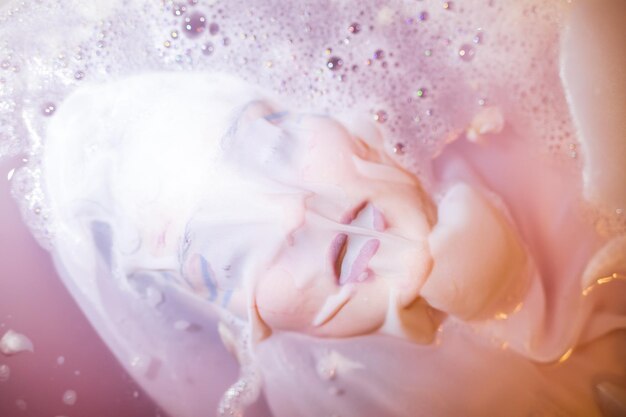 Close-up du visage d'une jeune femme couvert de textile dans la baignoire.