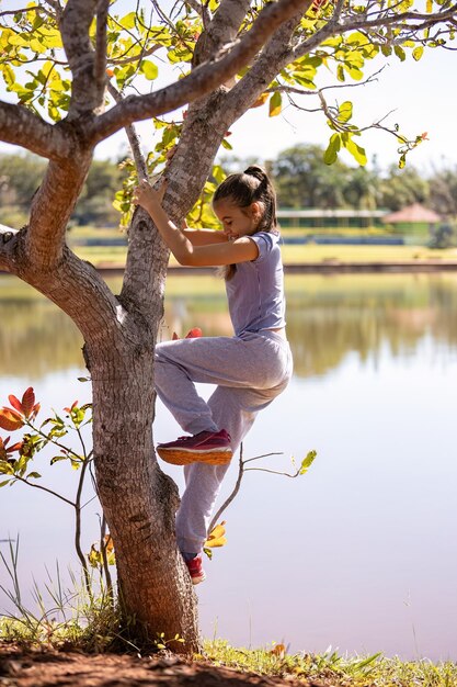 Close-up d'une enfant fille en vêtements gris jouant dans un arbre dans un parc avec une mise au point sélective