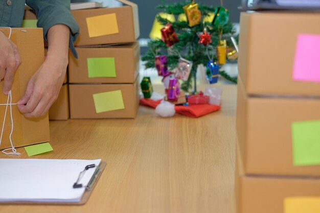 Photo close-up d'une femme d'affaires emballant une boîte sur la table pendant noël