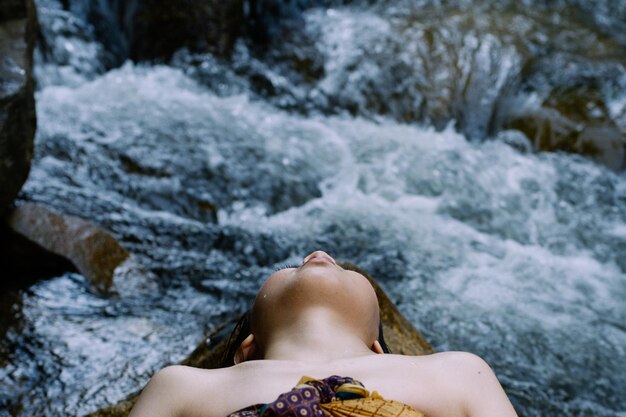 Photo close-up d'une femme allongée sur un rocher près d'une rivière
