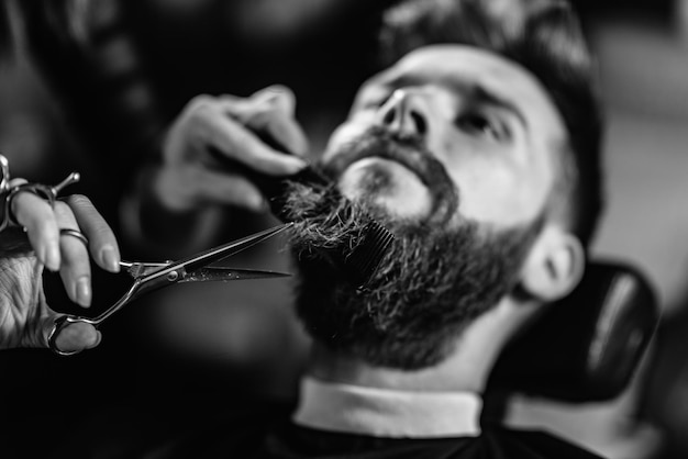 Photo close-up d'une femme coupant la barbe d'un homme au magasin