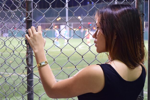 Photo close-up d'une femme debout près de la clôture en chaîne dans le stade