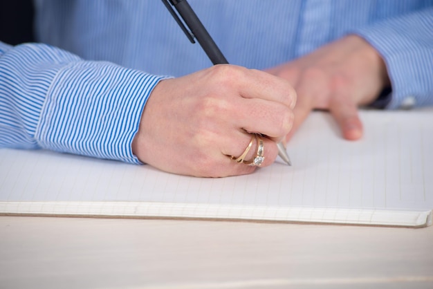 Close-up d'une femme écrivant dans un livre sur une table