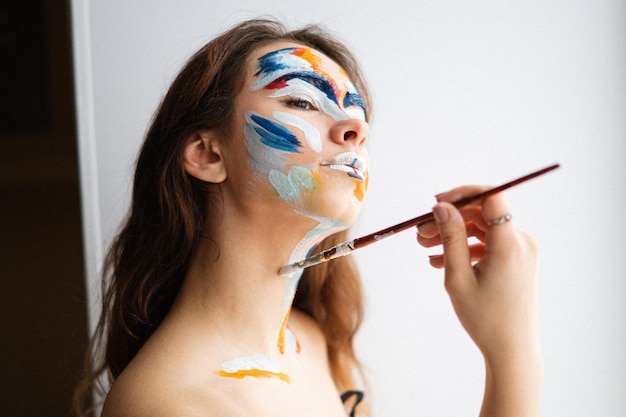 Close-up d'une femme peignant le visage contre le mur