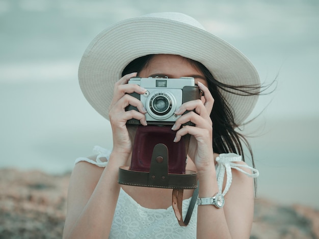 Close-up d'une femme photographiant avec un appareil photo analogique contre le ciel