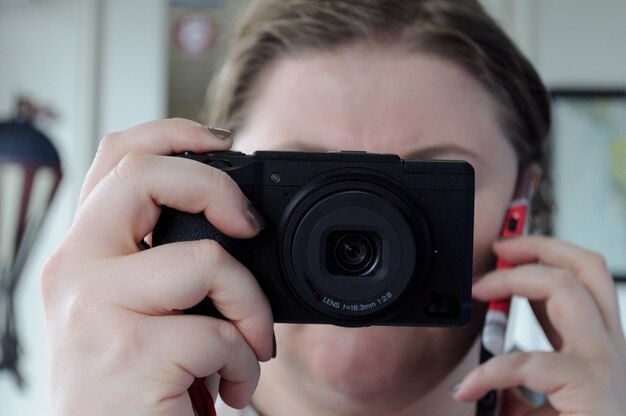 Photo close-up d'une femme photographiant à travers une caméra tout en parlant au téléphone portable