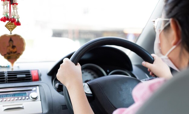 Photo close-up d'une femme portant un masque alors qu'elle conduit une voiture