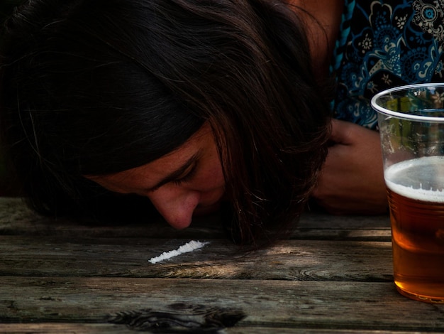 Close-up d'une femme qui prend de la cocaïne alors qu'elle est assise à table