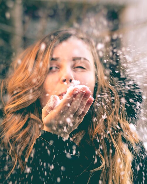 Photo close-up d'une femme soufflant de la neige