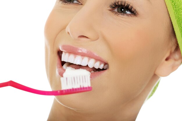 Photo close-up d'une femme souriante avec une brosse à dents sur fond blanc