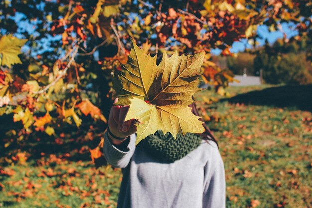 Close-up d'une femme tenant une feuille d'automne