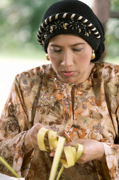 Photo close-up d'une femme tissant des feuilles alors qu'elle est assise dans un gazebo