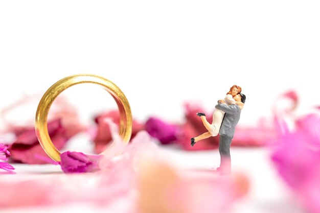 Photo close-up de figurines par anneau et de fleurs sur table sur fond blanc