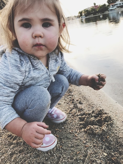 Close-up d'une fille accroupie sur le rivage