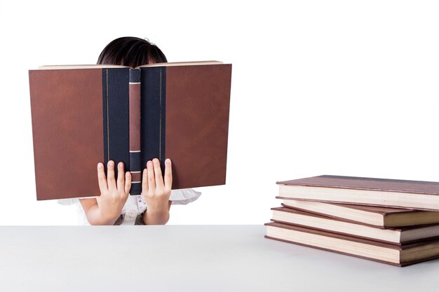 Photo close-up d'une fille lisant un livre assise sur un fond blanc