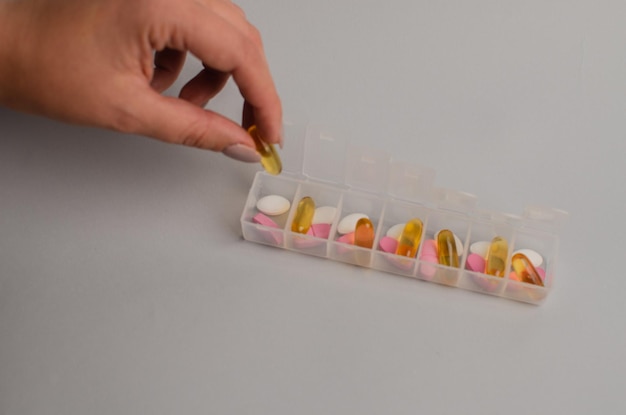 Photo close-up d'une fille méconnaissable triant des vitamines dans un concept de biohacking de l'organisateur de pilules