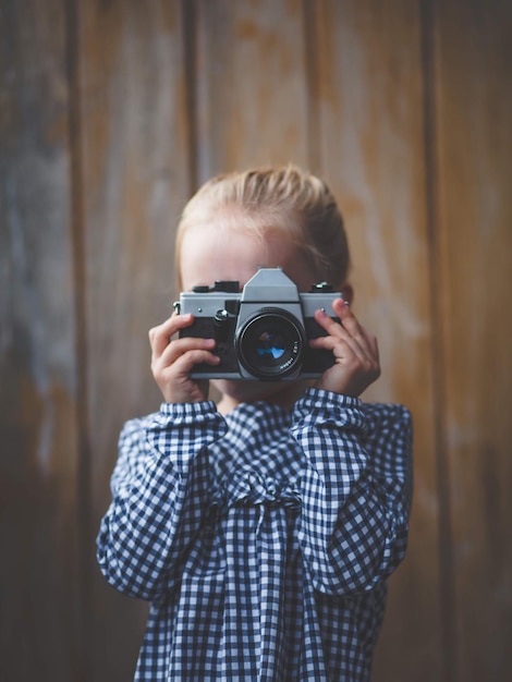 Close-up d'une fille photographiant avec une caméra contre le mur