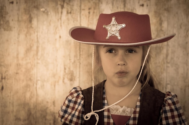 Close-up d'une fille portant un chapeau de cow-boy contre le mur