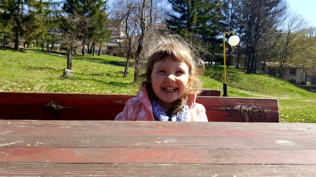 Close-up d'une fille souriante assise à une table de pique-nique dans un parc