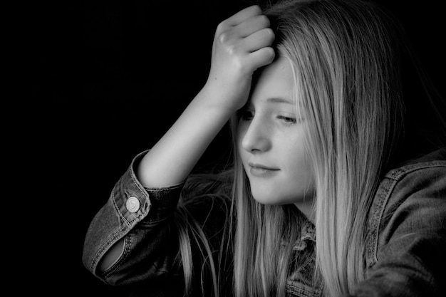 Photo close-up d'une fille avec la tête en main sur un fond noir