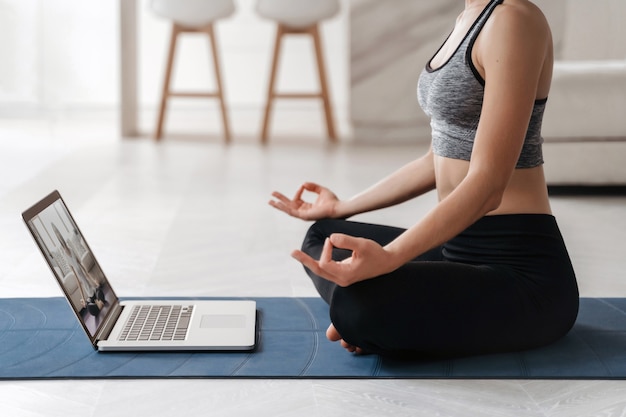 Close up fit woman coach a une formation en ligne vidéo sur Internet de hatha yoga, pratiquant la posture de Sukhasana