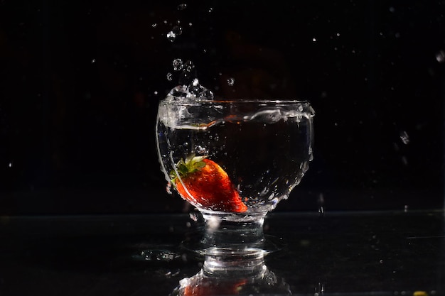 Photo close-up de fraise dans un bol rempli d'eau sur un fond noir