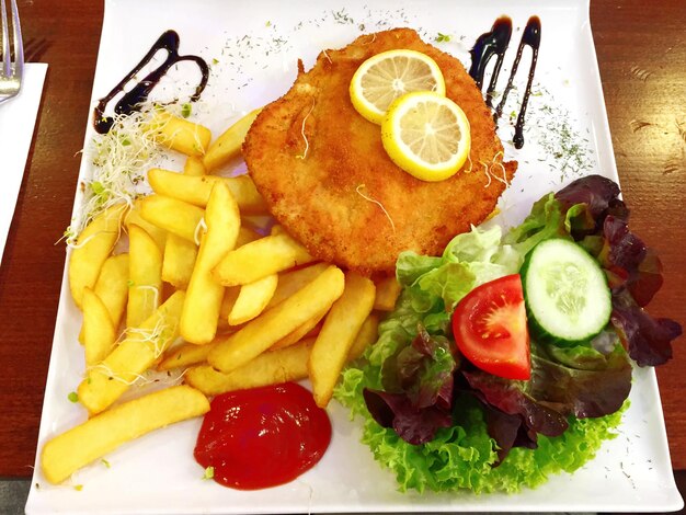 Photo close-up de frites et de hamburgers servis avec de la salade dans un plateau sur la table à l'intérieur