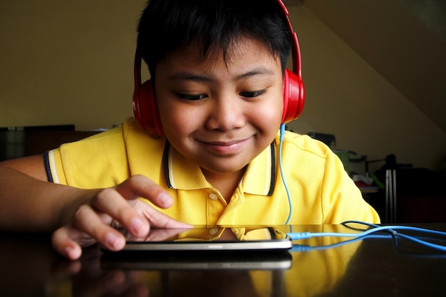 Photo close-up d'un garçon écoutant des écouteurs tout en utilisant un smartphone