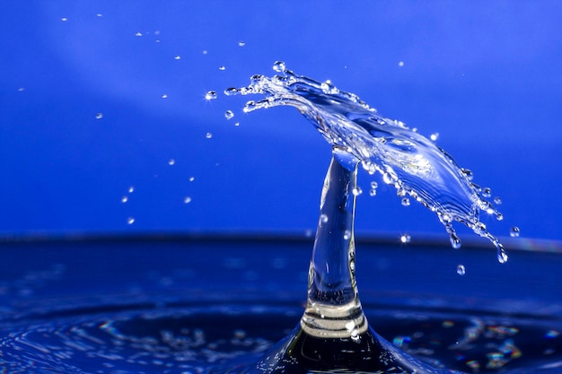 Close-up d'une goutte éclaboussant sur l'eau sur un fond bleu