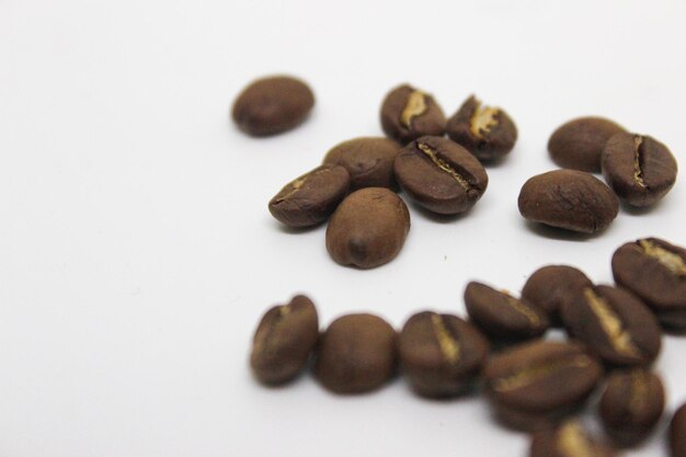 Close-up de grains de café torréfiés sur un fond blanc