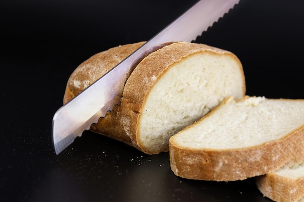Close up grand couteau coupe de minces morceaux de pain blanc à partir d'un pain rectangulaire