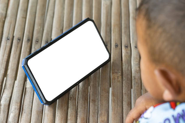 Close up hand child touch a Smartphone, Enfant jouant avec un téléphone à l'extérieur. Enfant tenant un smartphone dans les mains. Vue latérale d'un garçon de deux ans portant et regardant le mobile.