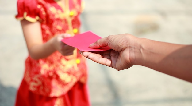 Close up hand donner de l&#39;argent dans une enveloppe rouge à la fille sur le nouvel an chinois