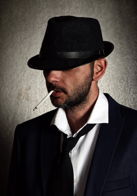 Photo close-up d'un homme adulte qui fume une cigarette contre un mur gris