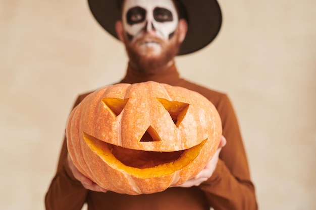 Close-up d'un homme barbu en costume de sorcier montrant le concept d'Halloween de jackolantern fait à la main