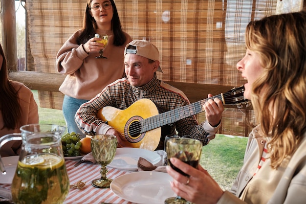 Photo close-up d'un homme jouant de la guitare et chantant à la guitare lors d'un dîner en famille en plein air