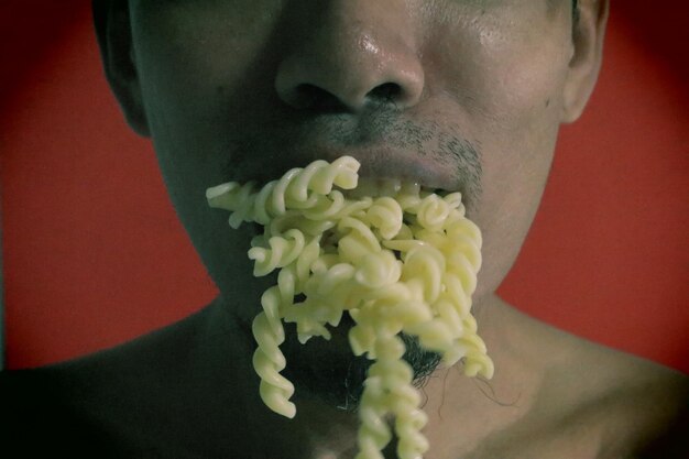 Close-up d'un homme avec des pâtes sur fond rouge