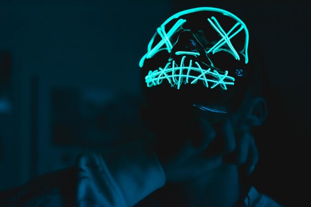 Photo close-up d'un homme portant une casquette lumineuse debout dans une chambre noire